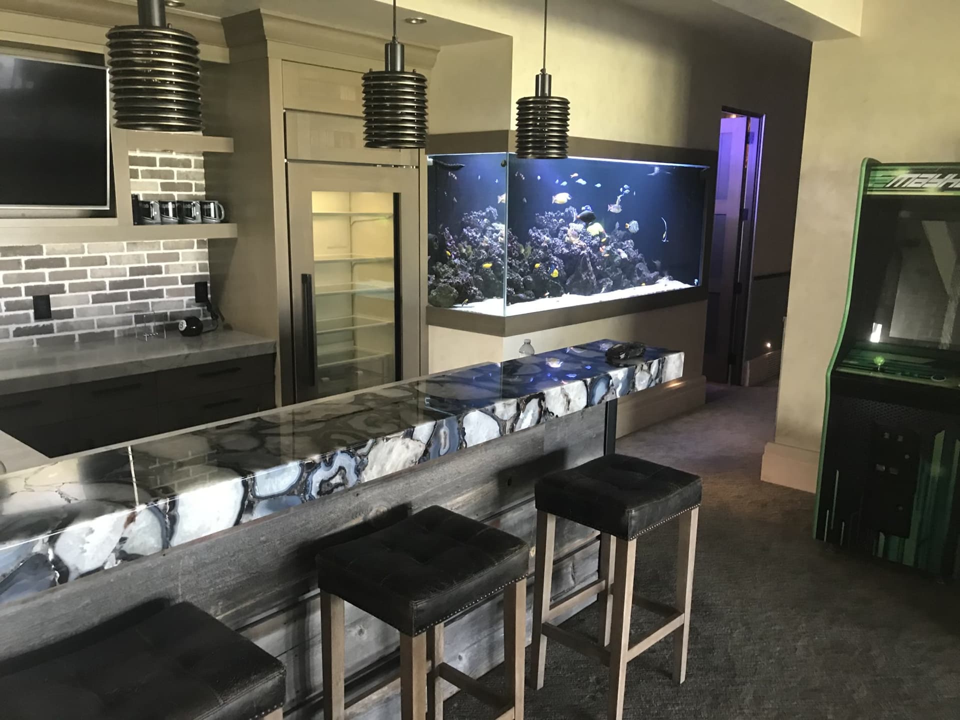 A large reef aquarium integrated into a finished bar and entertainment room